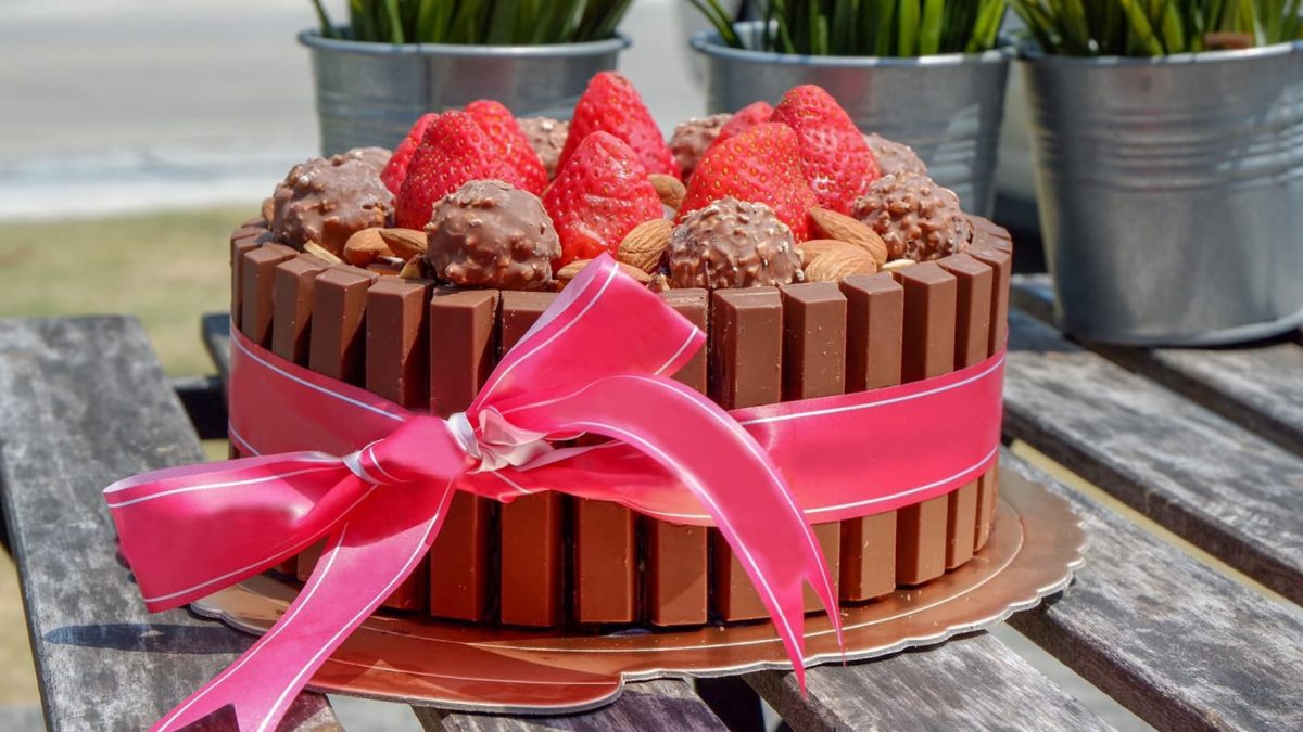 Kit-Kat Cheesecake Torte auf einem Holztisch mit pinker Schleife.