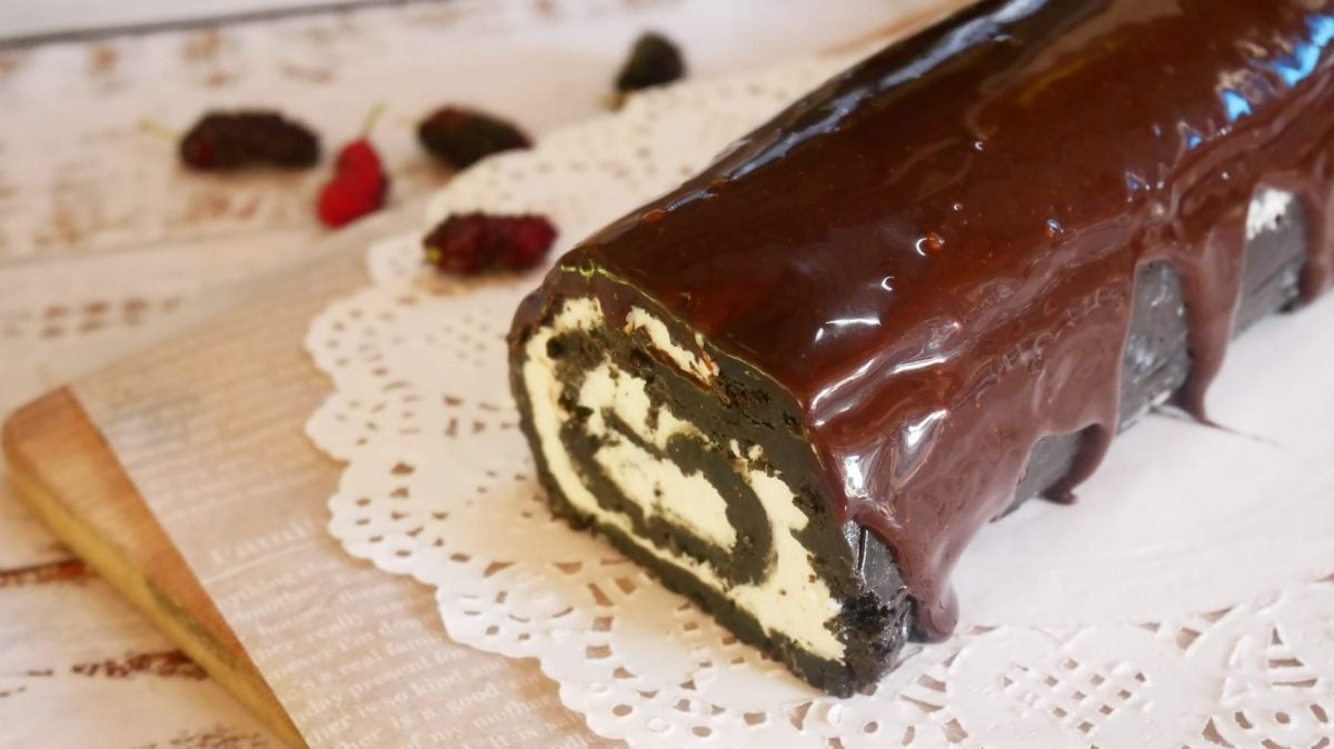 Auf einem Tisch liegt eine Oreo-Suhshi Rolle die mit Schokolade überzogen ist.