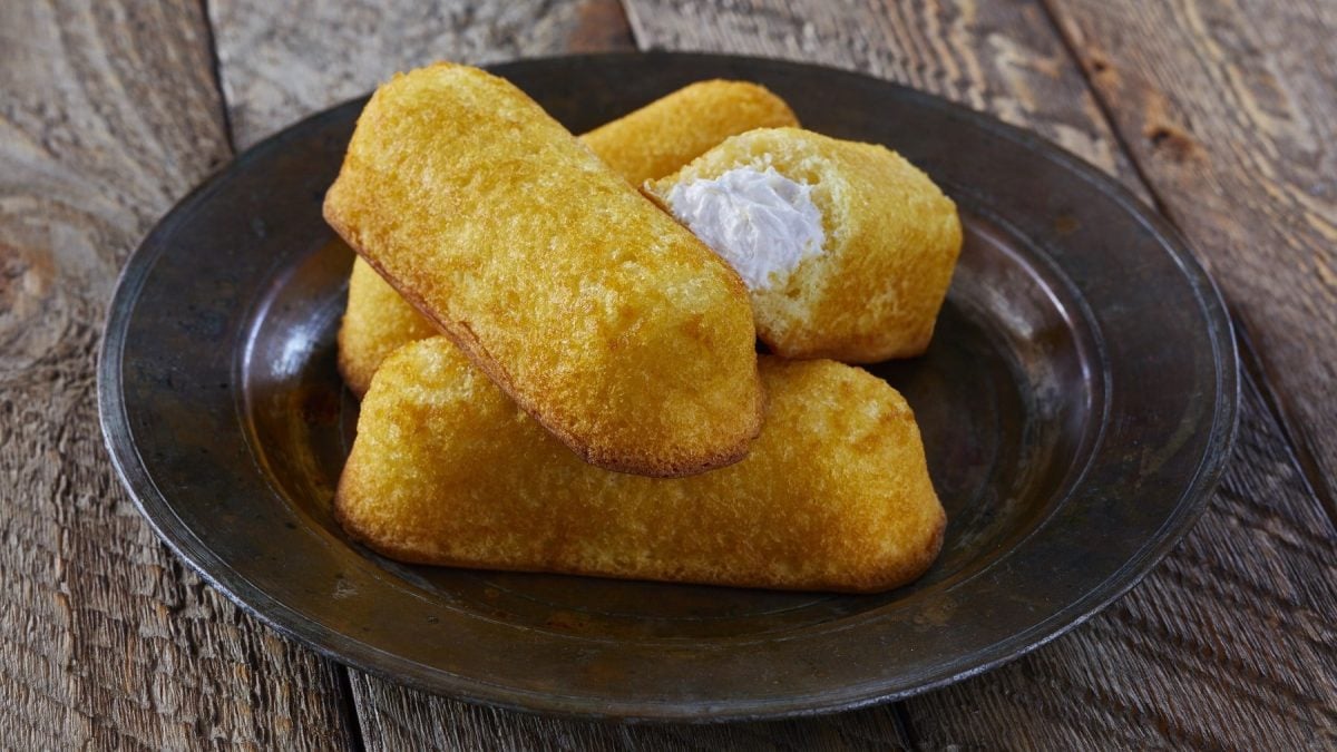 Twinkies selbst machen. Twinkies gefüllt mit einer Vanille-Sahne-Creme auf einem Teller auf hölzernem Untergrund.