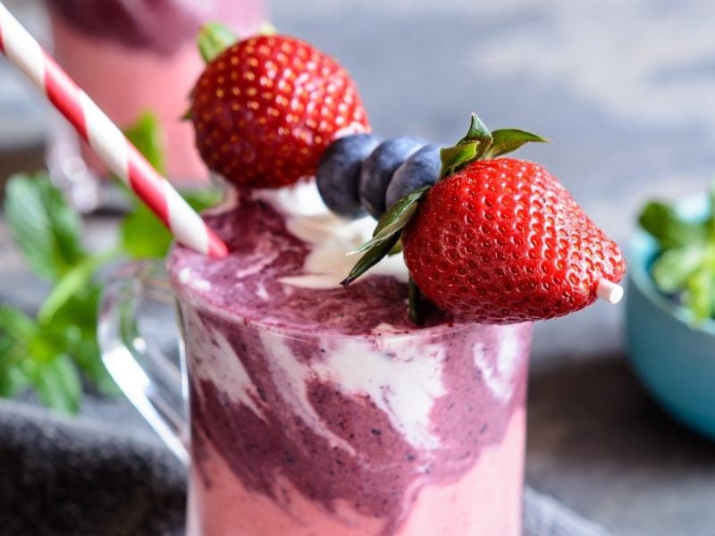 Erdbeer-Heidelbeer-Smoothie mit Joghurt mit frischen Früchten serviert.