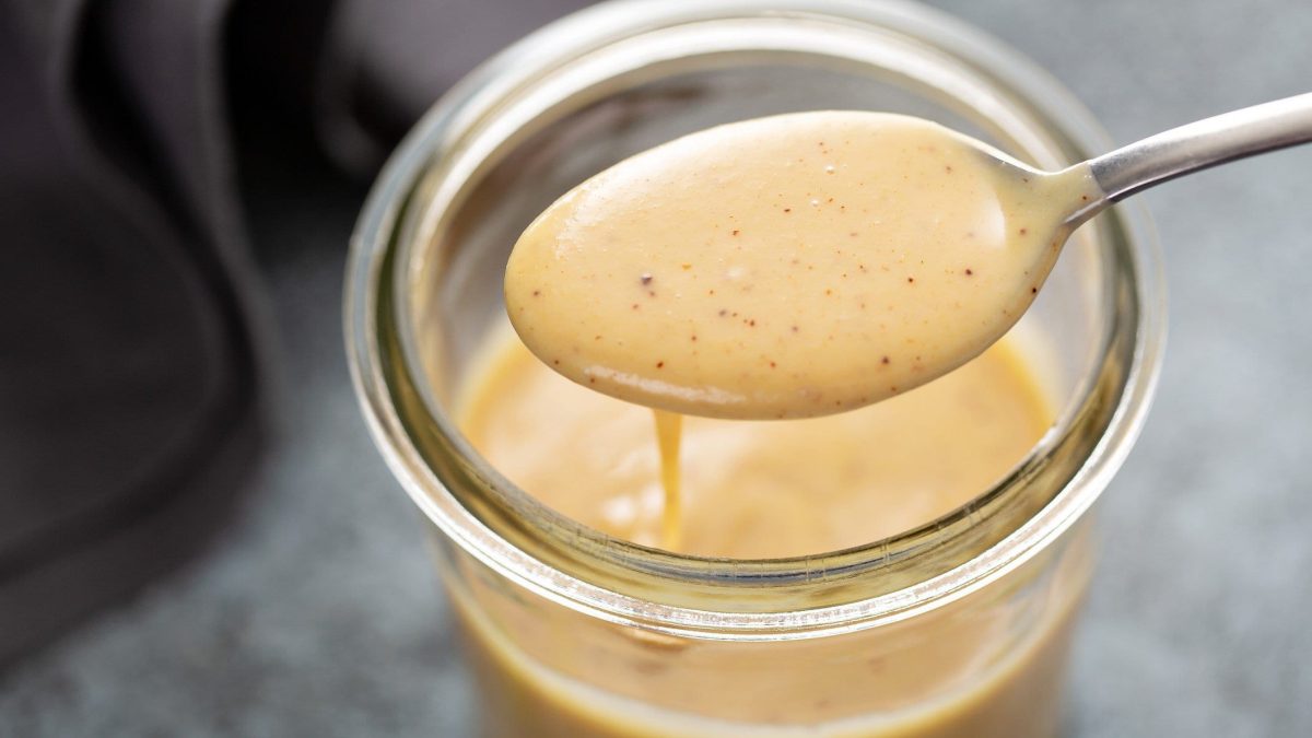 Honig-Senf-Sauce in einer Schale und auf einem Löffel.
