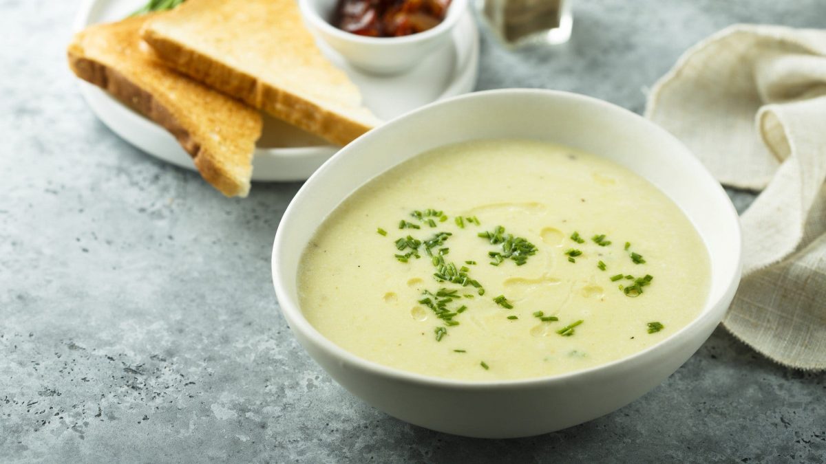 Spargelcremesuppe in einer weißen Schale. Im Hintergrund weitere Zutaten.