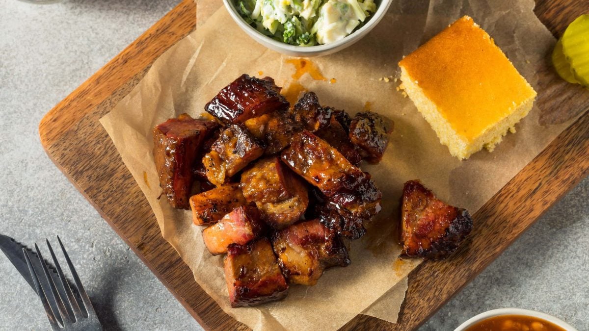 Burnt Ends mit allerhand Beilagen auf einem Holzbrett