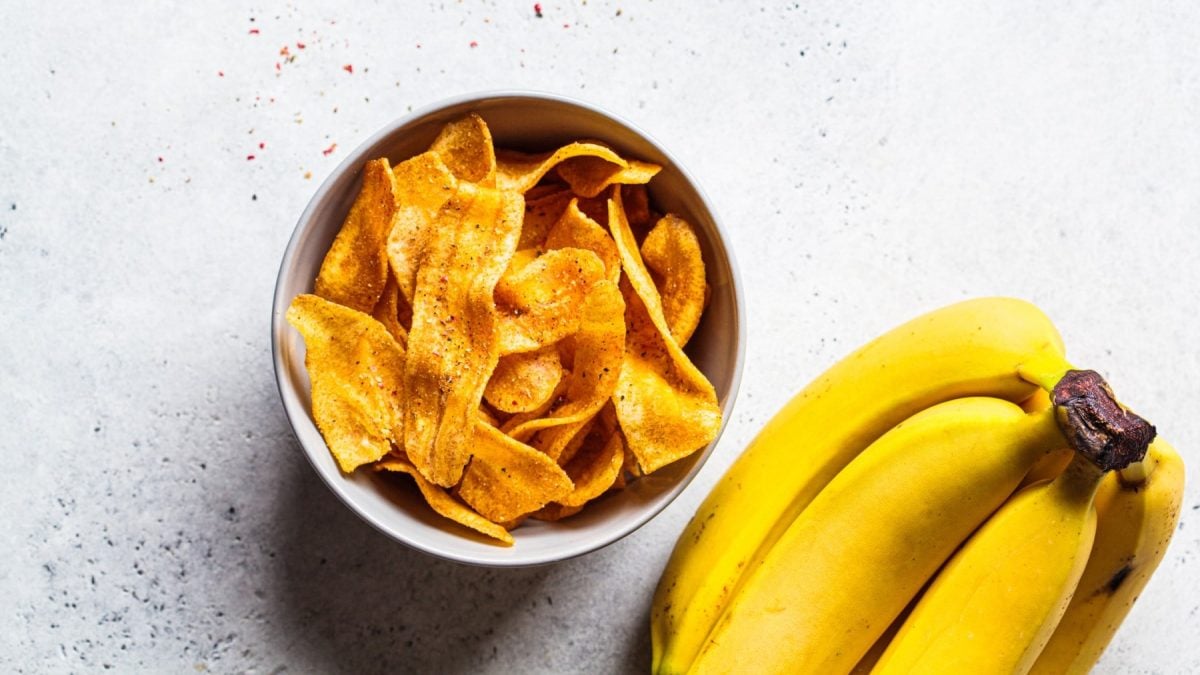 Herzhafte Bananenchips in einer weißen Schale. Daneben Bananen.