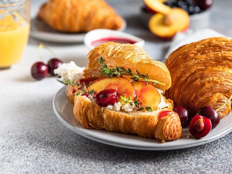 zwei Kirsch-Croissant mit Nektarine und Ricotta leigen auf einem Teller.