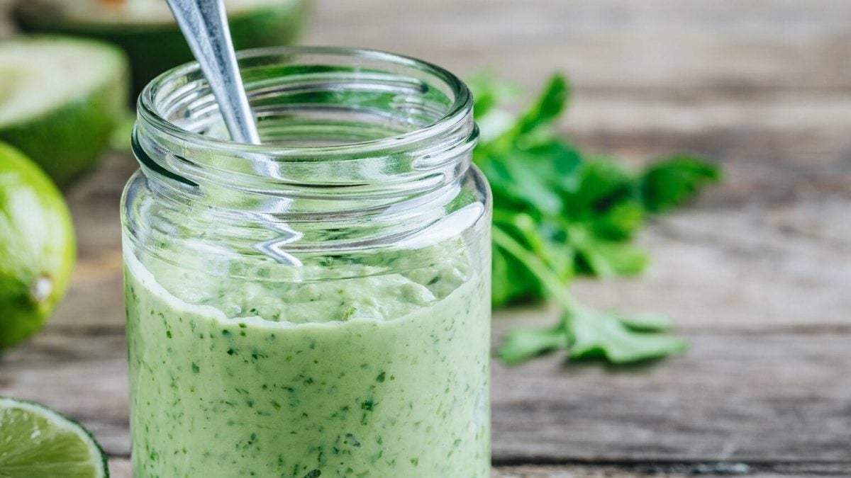 In einem Glas ist eine selbstgemachte Koriander-Mayonnaise mit Limetten.