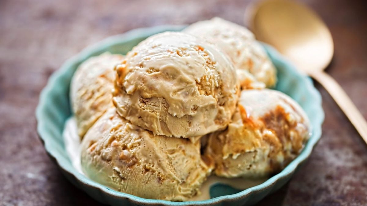 Fünf Kugeln Miso-Eis mit Karamell in einer hellblauen Schale auf dunklem Untergrund.