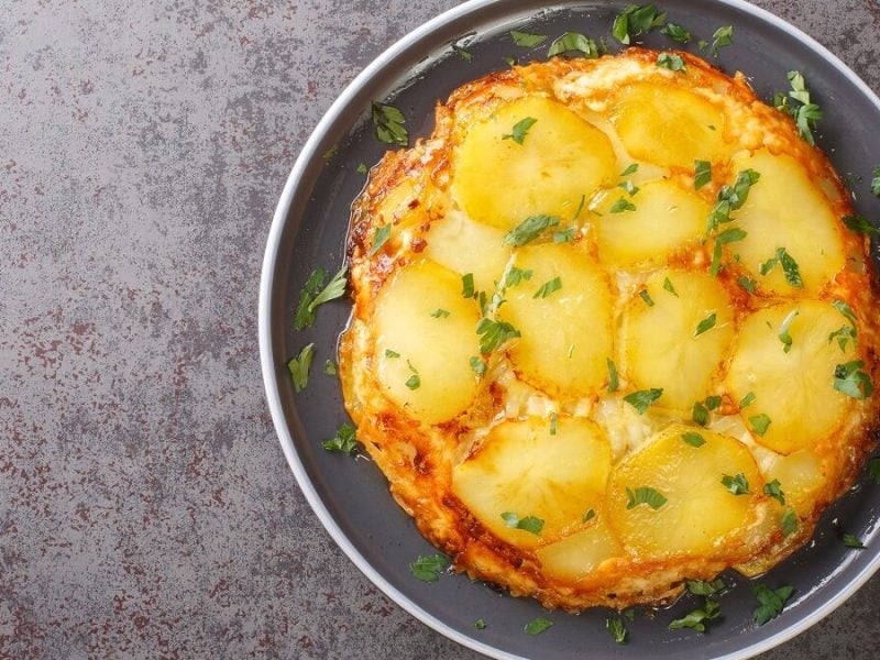 AUs der Vogelperspektive: Eine Pfanne mit Pan Haggerty steht auf einem dunklem Untergrund. Es handelt sich um ein Kartoffelgericht.