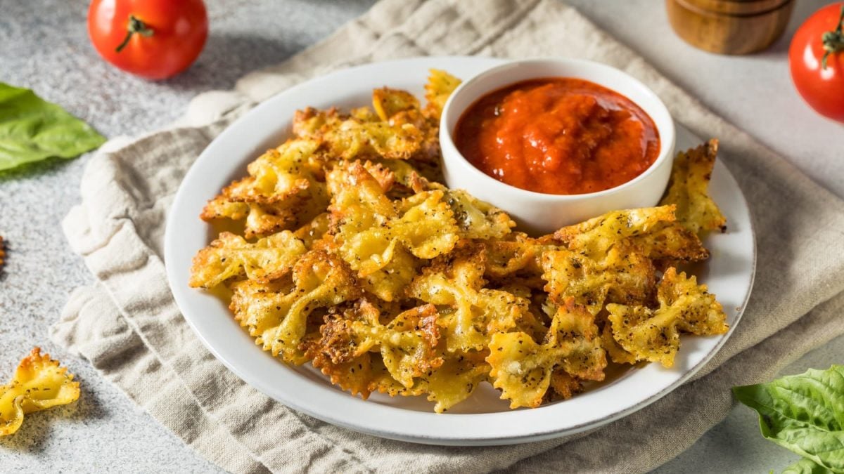 Pasta-Chips auf einem Teller. Daneben verschiedene Zutaten.