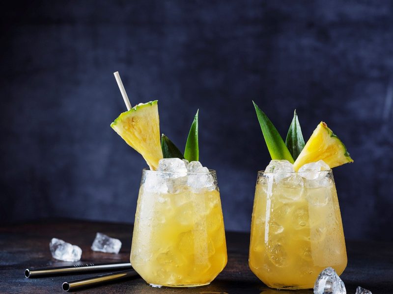 Pisco Pineapple Punch vor dunklem Hintergrund mit Ananas und Aloes Vera Dekoration. Frontalansicht.