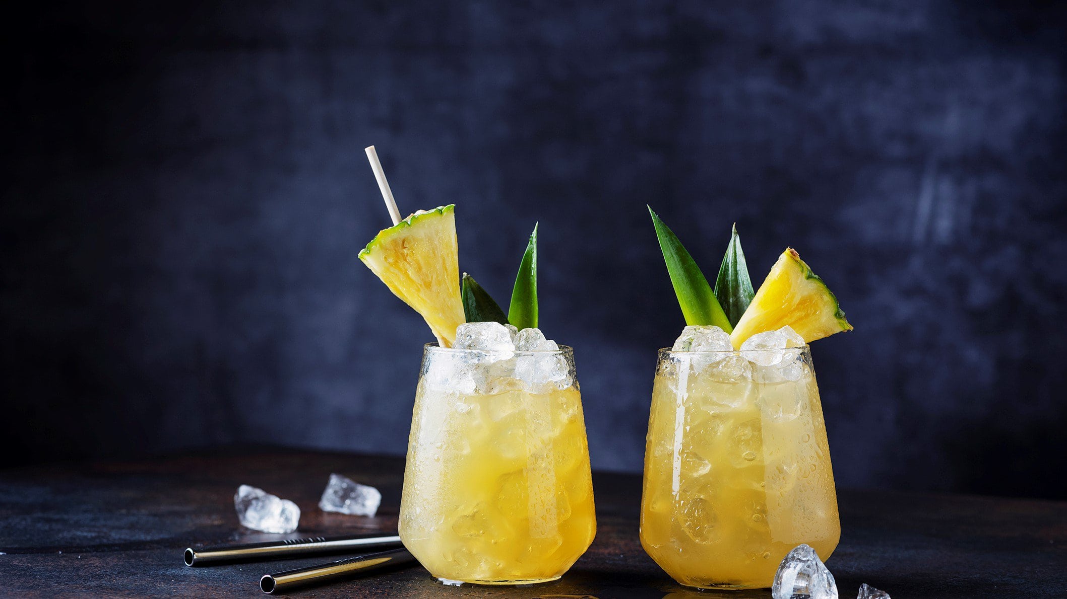 Pisco Pineapple Punch vor dunklem Hintergrund mit Ananas und Aloes Vera Dekoration. Frontalansicht.
