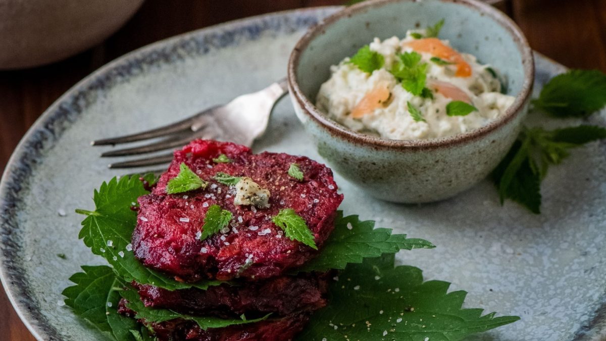 Rote Bete Puffer mit Brennesseln auf einem hellblauem Teller.