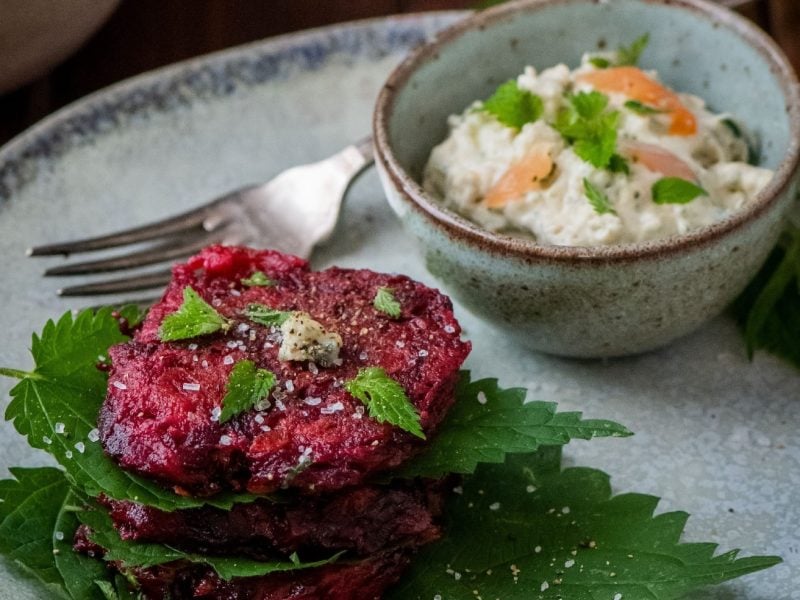 Rote Bete Puffer mit Brennesseln auf einem hellblauem Teller.