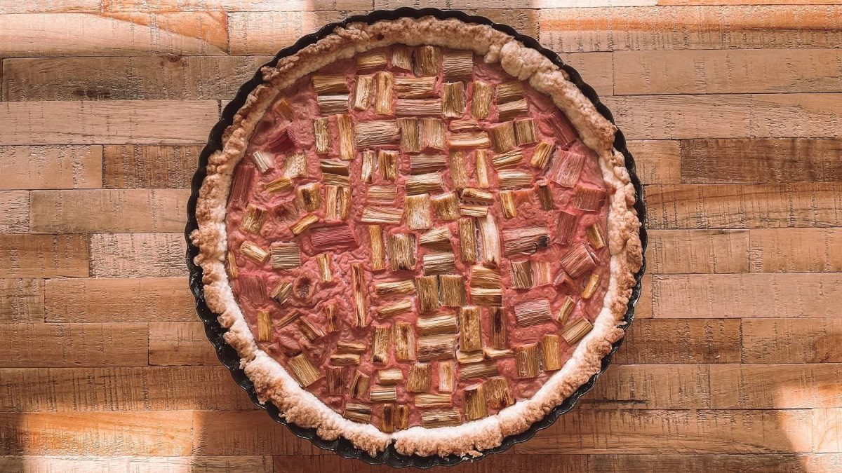 Eine vegane Erdbeer-Rhabarber-Tarte in einer Form auf Holz in der Draufsicht.