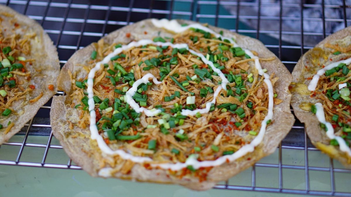 Drei vietnamesische Pizzen auf einem Metallgitter über einem Grill.