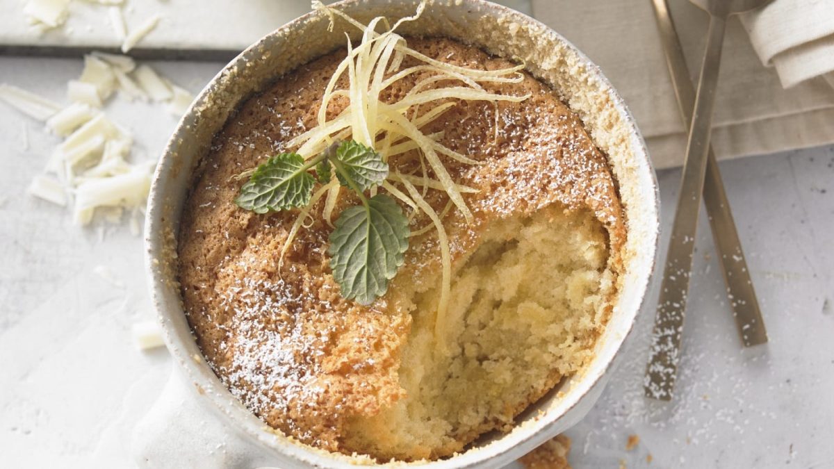 In einer Kuchenform ist ein Caprese al Limoni serviert. Er ist fluffig und mit Puderzucker und Zitronenabrieb verziert.