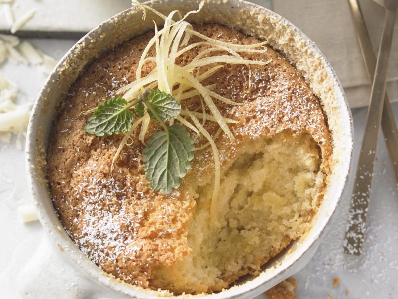 In einer Kuchenform ist ein Caprese al Limoni serviert. Er ist fluffig und mit Puderzucker und Zitronenabrieb verziert.