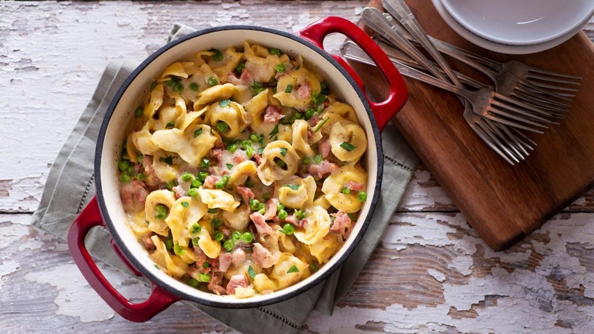 Kochtopf gefüllt mit One-Pot-Tortellini in Schinken-Sahne-Sauce mit Erbsen
