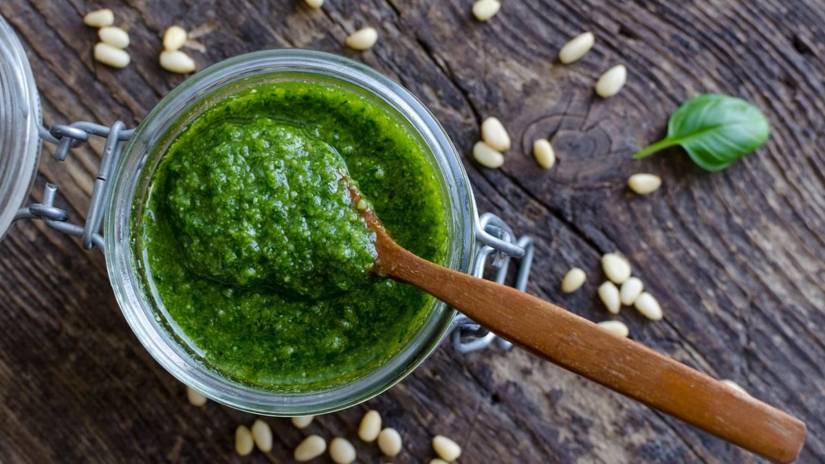 Pesto genovese mit Pinienkernen und Basilikum auf Holzuntergrund.