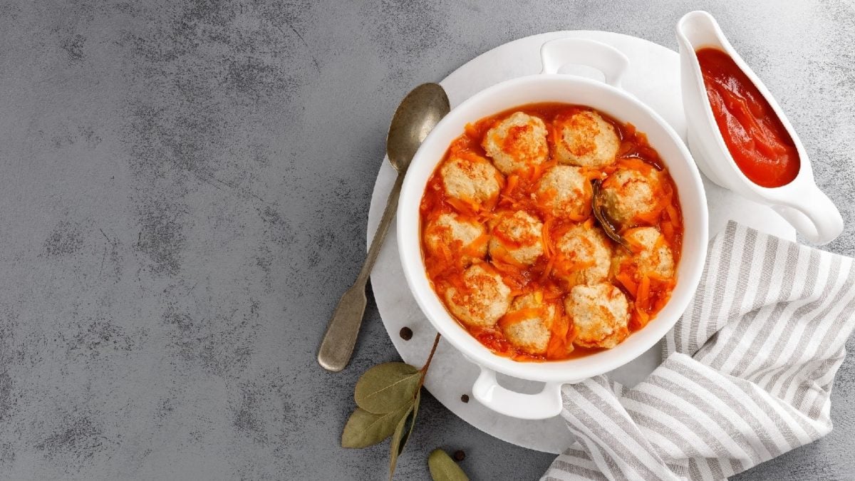 Fischfrikadellen in Tomatensauce auf einem gestreiften Küchentuch auf einem grauen Betontisch