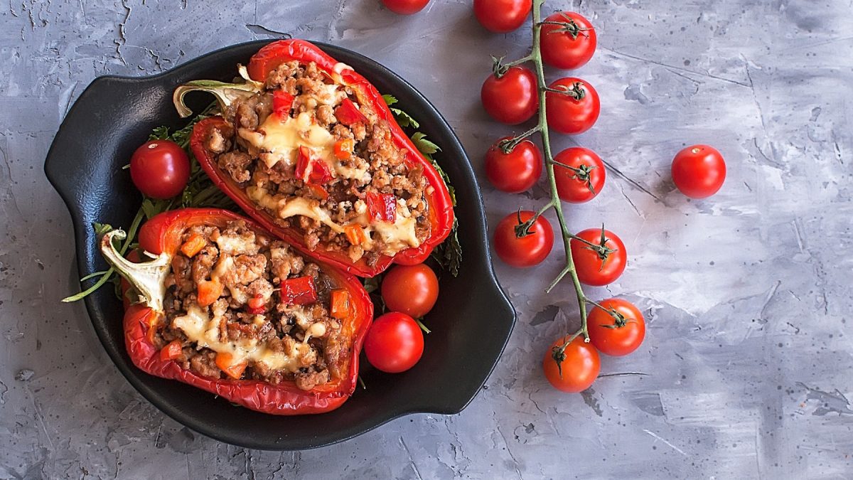 Gefüllte Paprika mit Hackfleisch überbacken mit Käse auf grauem Untergrund