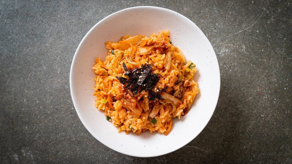 Ein Teller mit Kimchi Fried Rice und Nori-Streifen in einer weißen Schüssel auf grauem Hintergrund