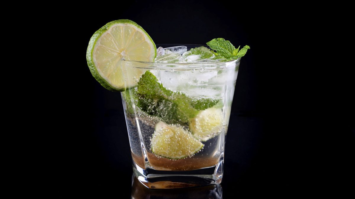 Ein Glas Mojito vor einem komplett schwarzen Hintergrund.
