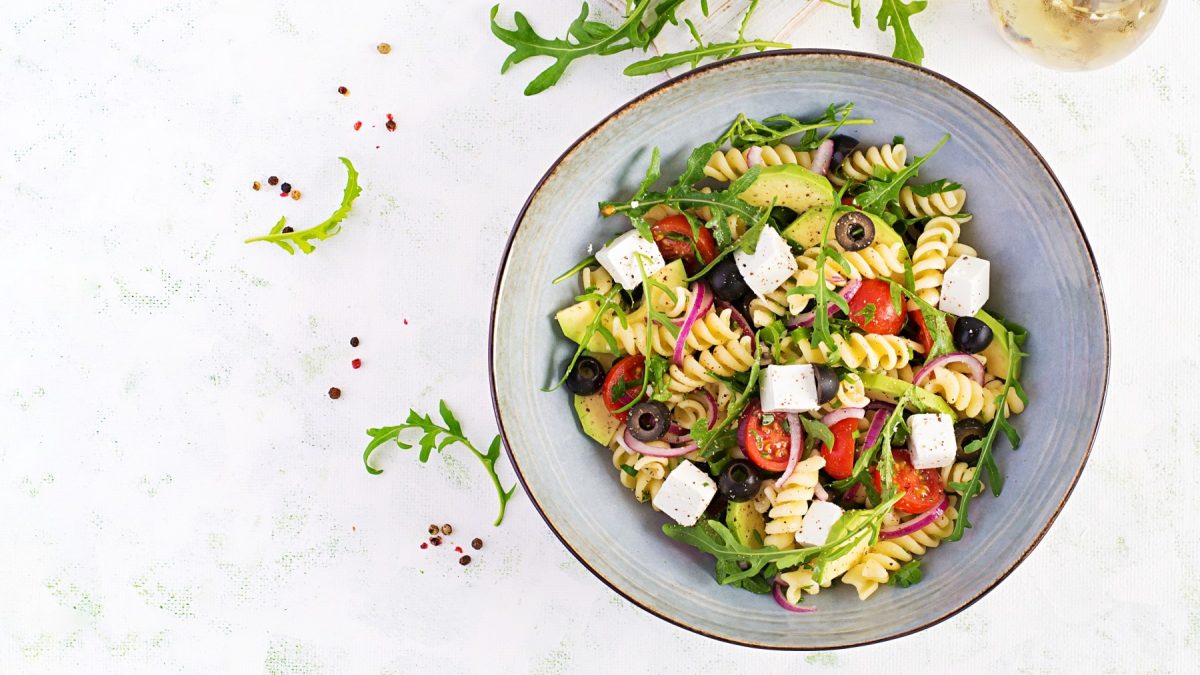 Nudelsalat mit Feta und Oliven in einer blaugrauen Schüssel.