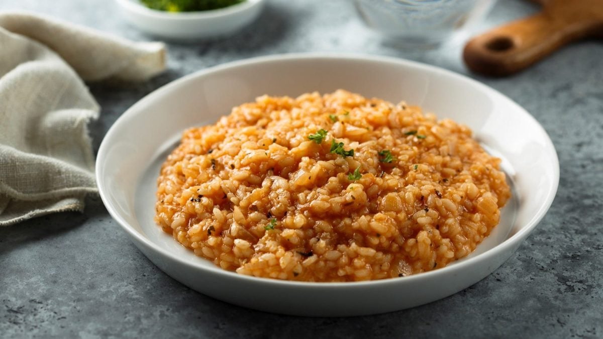 ein Teller veganes Tomatenrisotto mit frischen Kräutern bestreut.