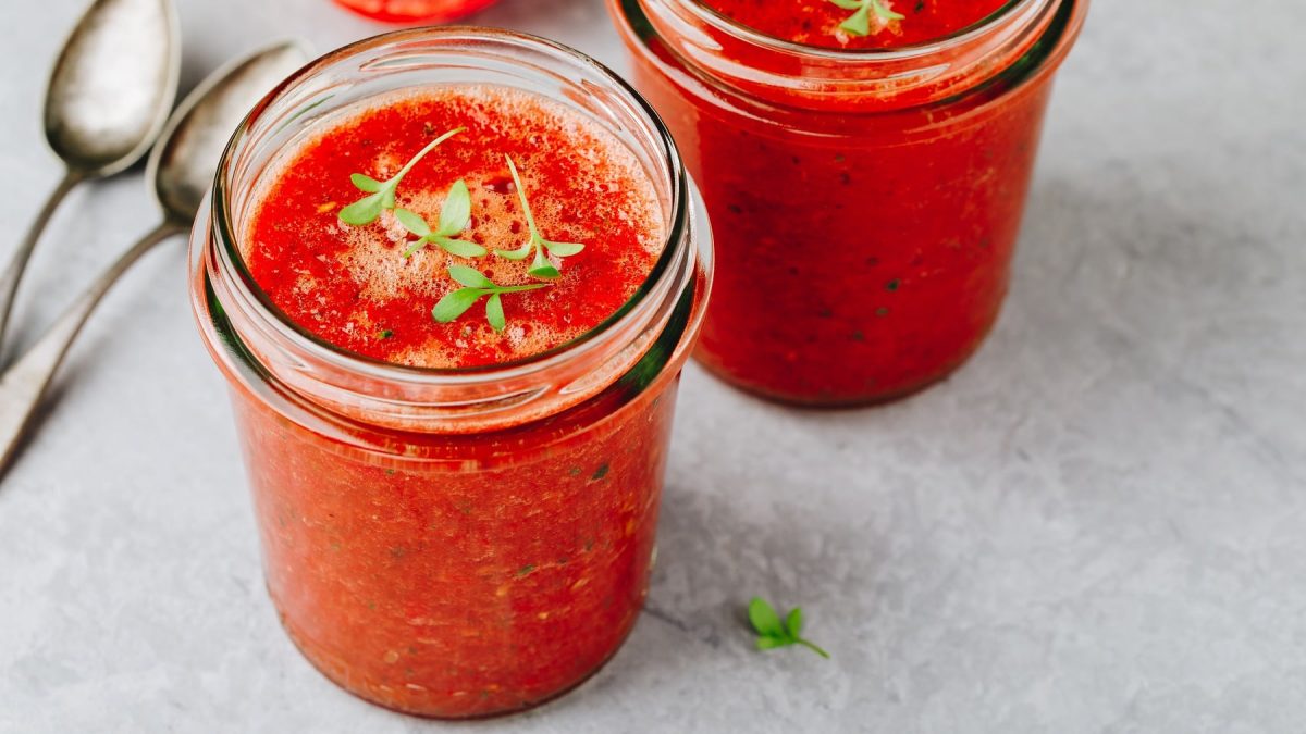 Zwei Gläser Wassermelonen-Gazpacho mit Kresse bestreut, daneben zwei Löffel.