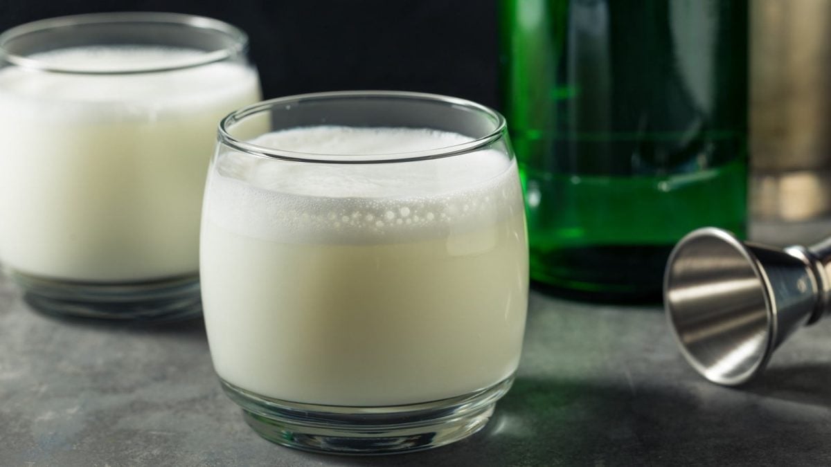 Yakult-Soju-Cocktail in einem weißen Glas neben einer grünen Flasche