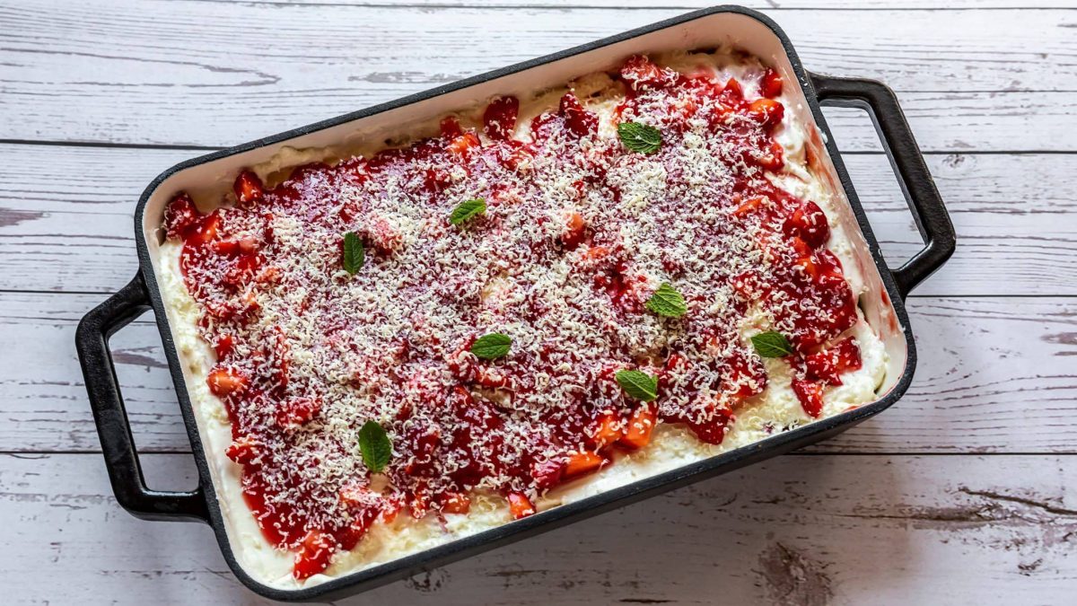 Erdbeerlasagne in schwarz-weißer Form auf hellem Holz.