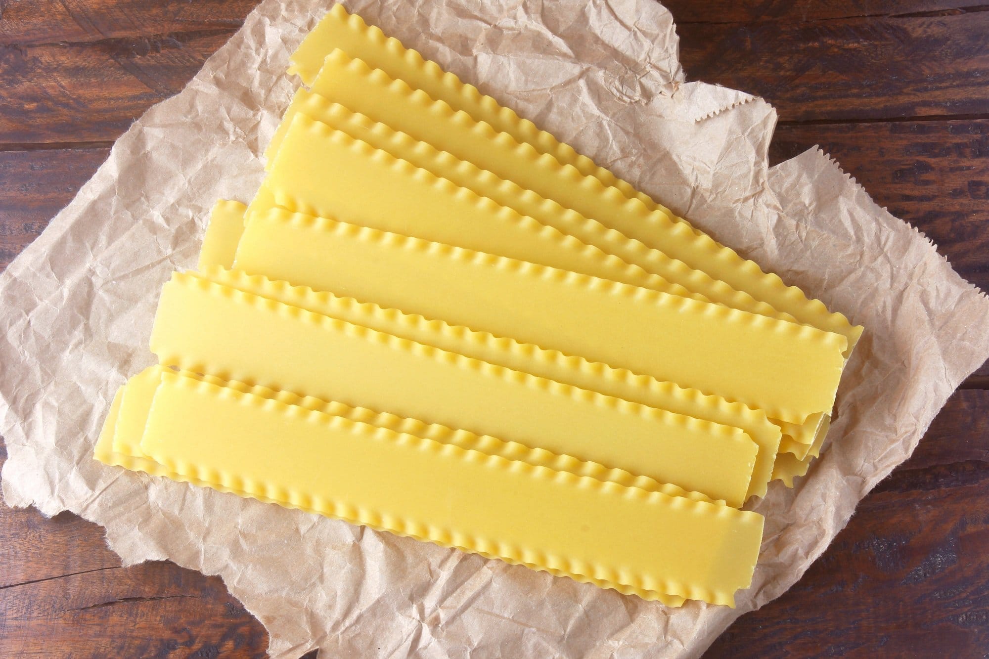 Lange Lasagnestreifen auf hölzernem Untergrund.