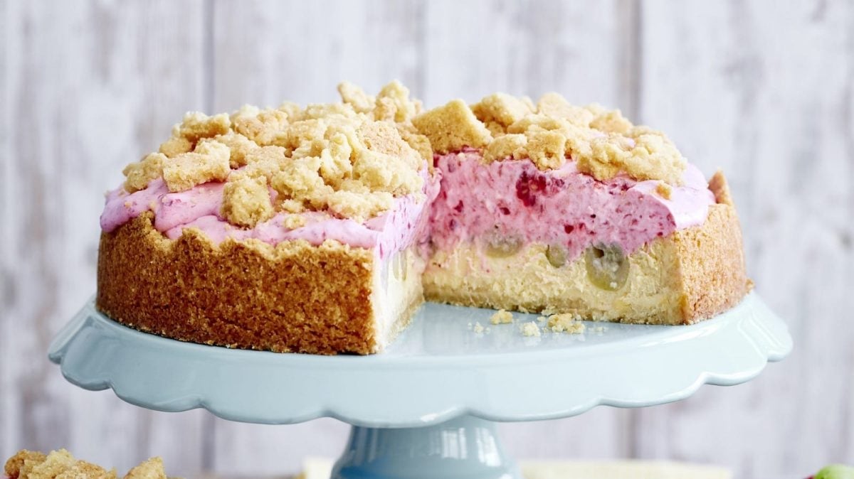 Auf einem Tortenteller steht eine Stachelbeer-Quark-Streuseltorte. Sie ist mit Streusel überzogen.