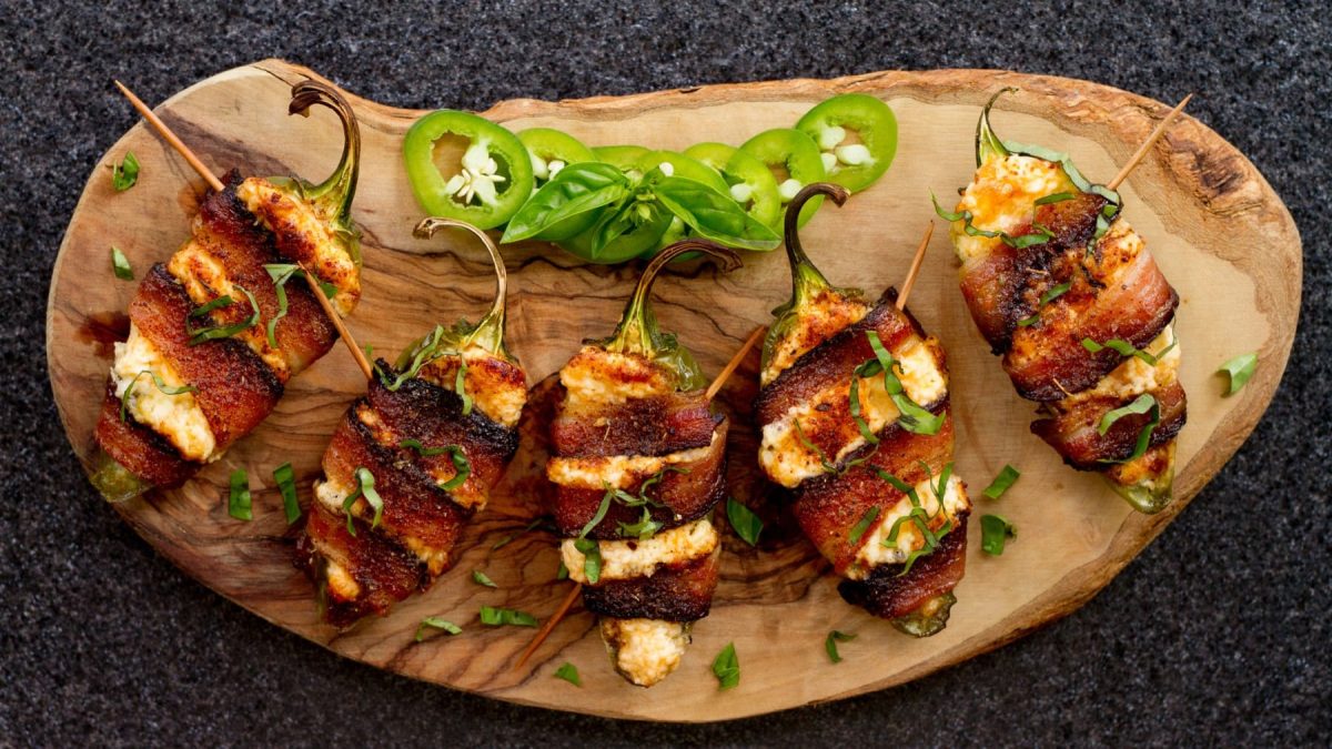Bacon Jalapeño Poppers liegen auf einem rundlichen Holzbrett.