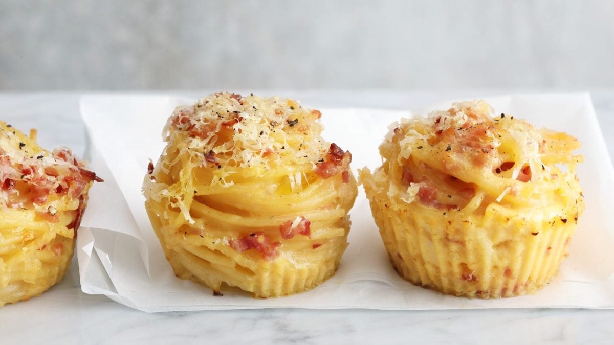Drei Carbonara-Muffins auf einem hellgrauen Tisch mit einer weißen Serviette und hellgrauem Hintergrund.