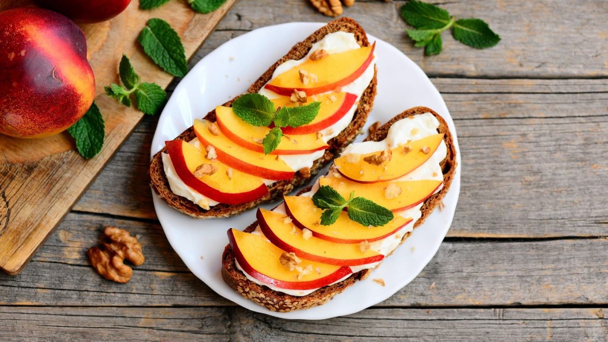 Ein weißer Teller mit Brot mit Nektarine und Ziegenfrischkäse