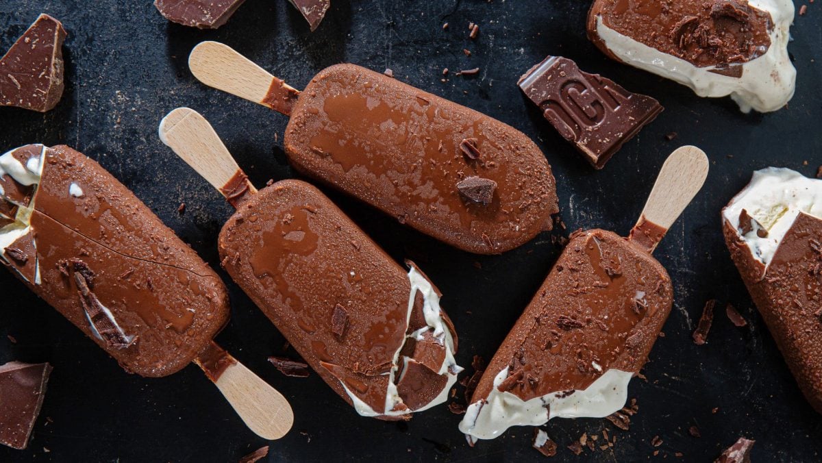 Selbst gemachte Eis am Stiel nach Magnum Art auf schwarzem Hintergrund. Eis teilweise angebrochen und Stücken von Schokolade. Aufnahme aus der Vogelperspektive.