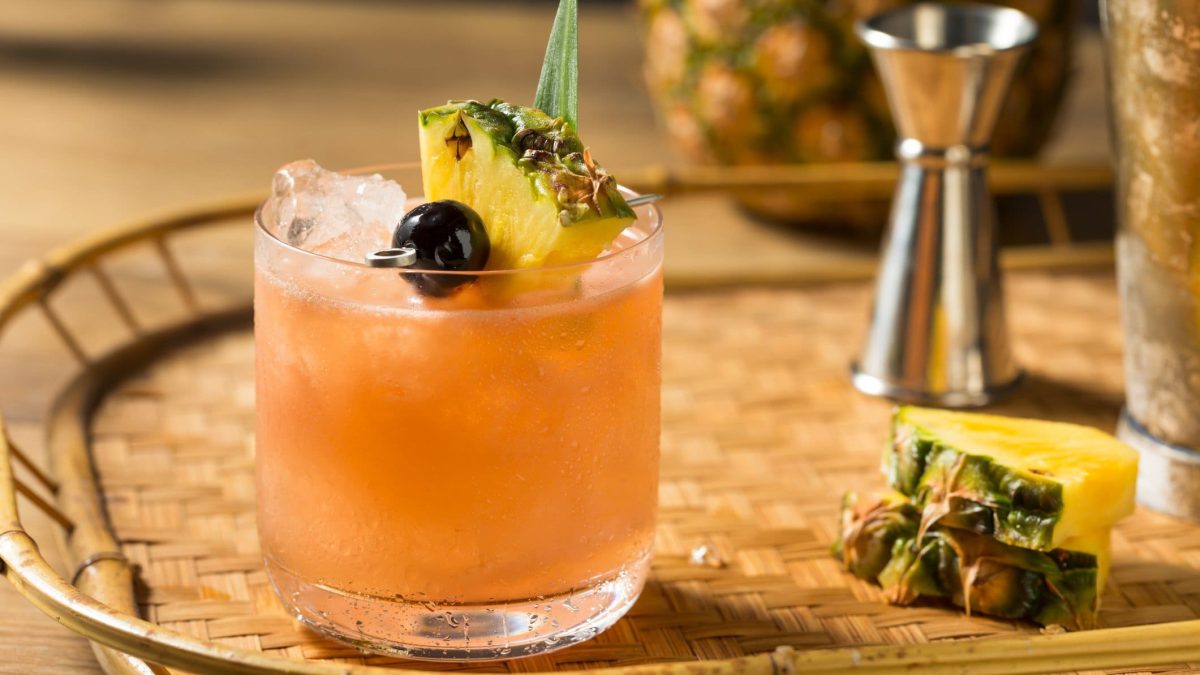 Mai Tai mit Deko auf Tablett mit Ananas und Bartools. Frontalansicht.