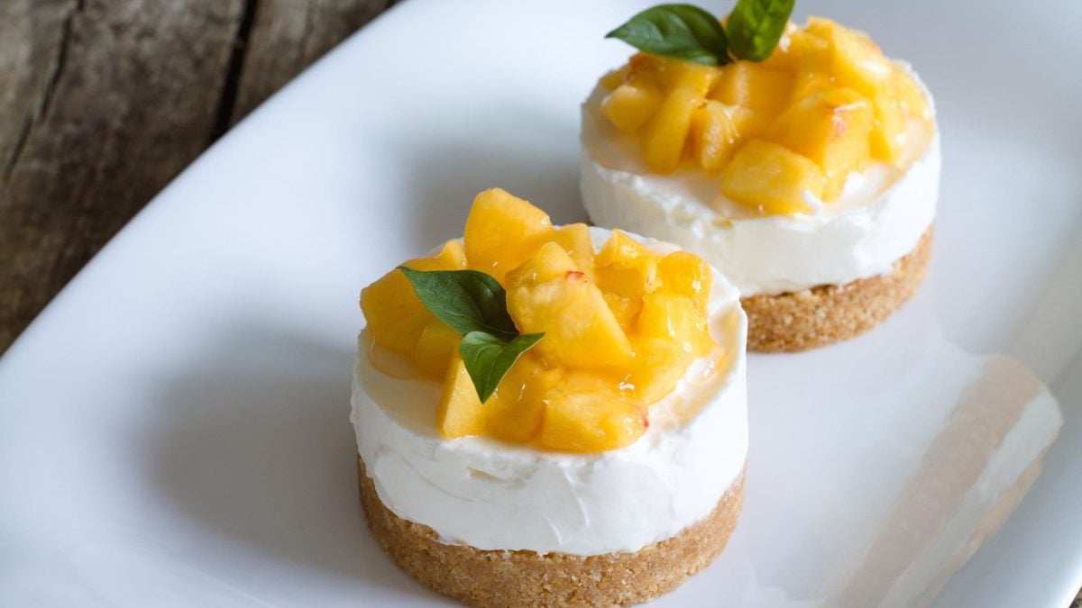 No Bake Frozen Joghurt Cake mit flambierter Ananas auf weißem Teller. Fronatlansicht.