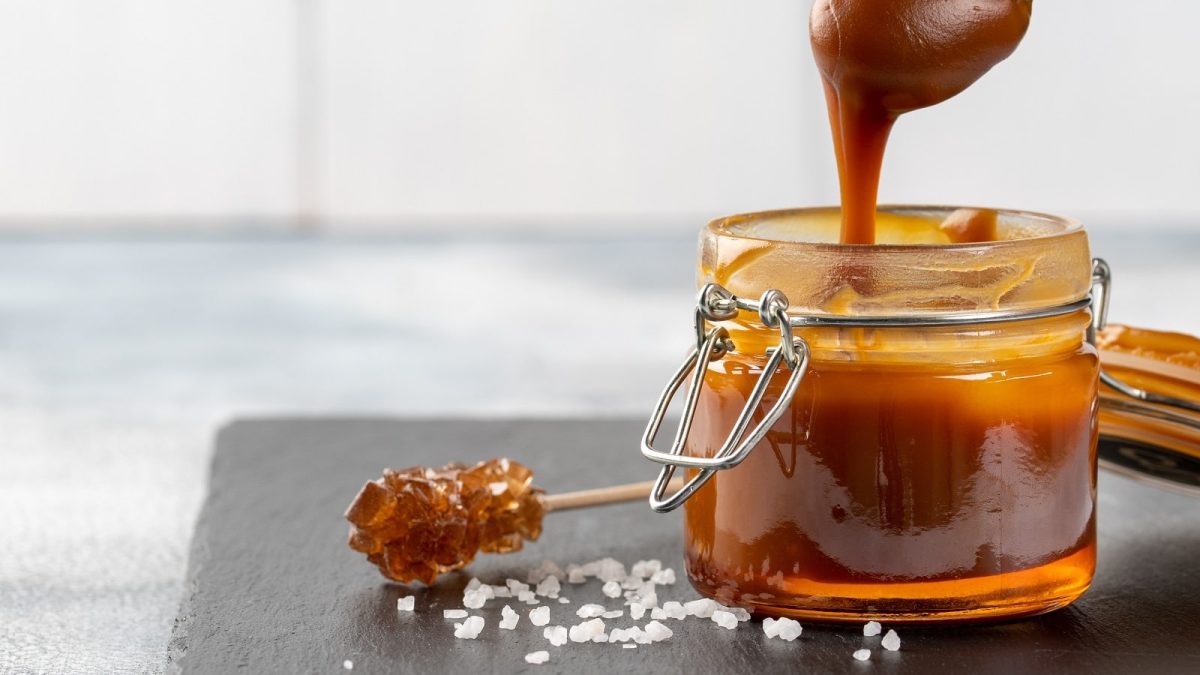 Ein Weckglas mit Salted-Caramel-Aufstrich und Meersalz auf einer schwarzen Schieferplatte.