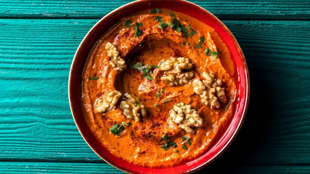 Eine Schüssel vegane Tomatenbutter mit Walnüssen und gehackten Kräutern in der Draufsicht.
