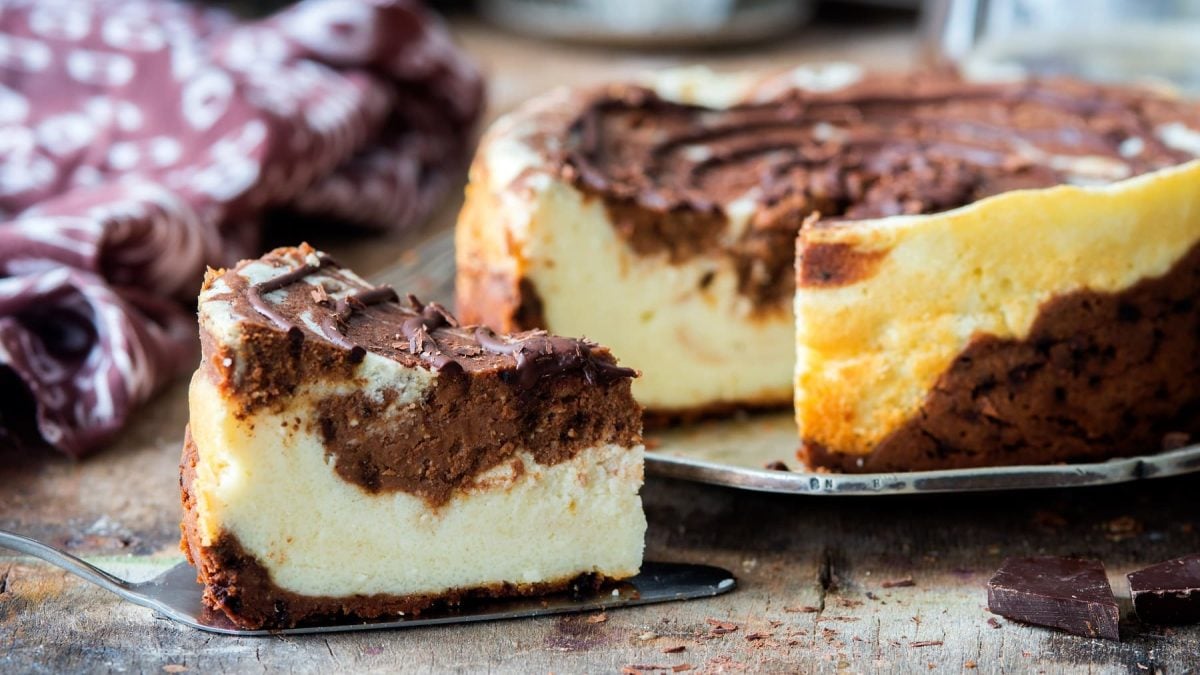 Ein Stück veganer russischer Zupfkuchen auf einem Tortenheber, dahinter steht der restliche Kuchen.