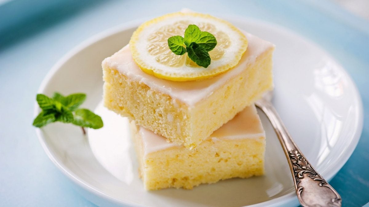 Zwei Stück Zitronenkuchen vom Blech auf weißem Teller.