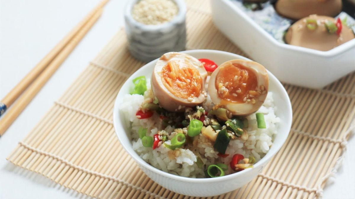 Eine Schüssel mit Mayak Eggs auf Reis neben einem Paar Stäbchen