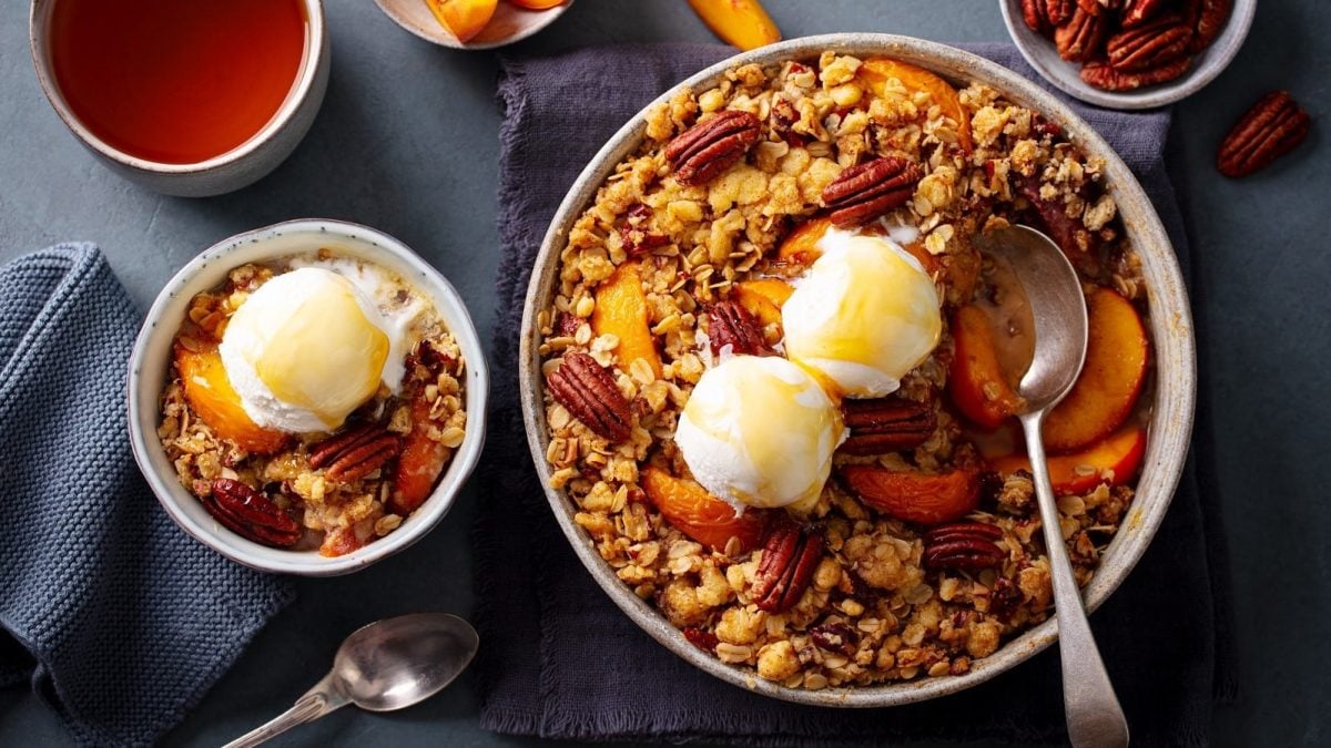 Eine Kuchenform mit Pfirsich-Crumble und Vanilleeis.