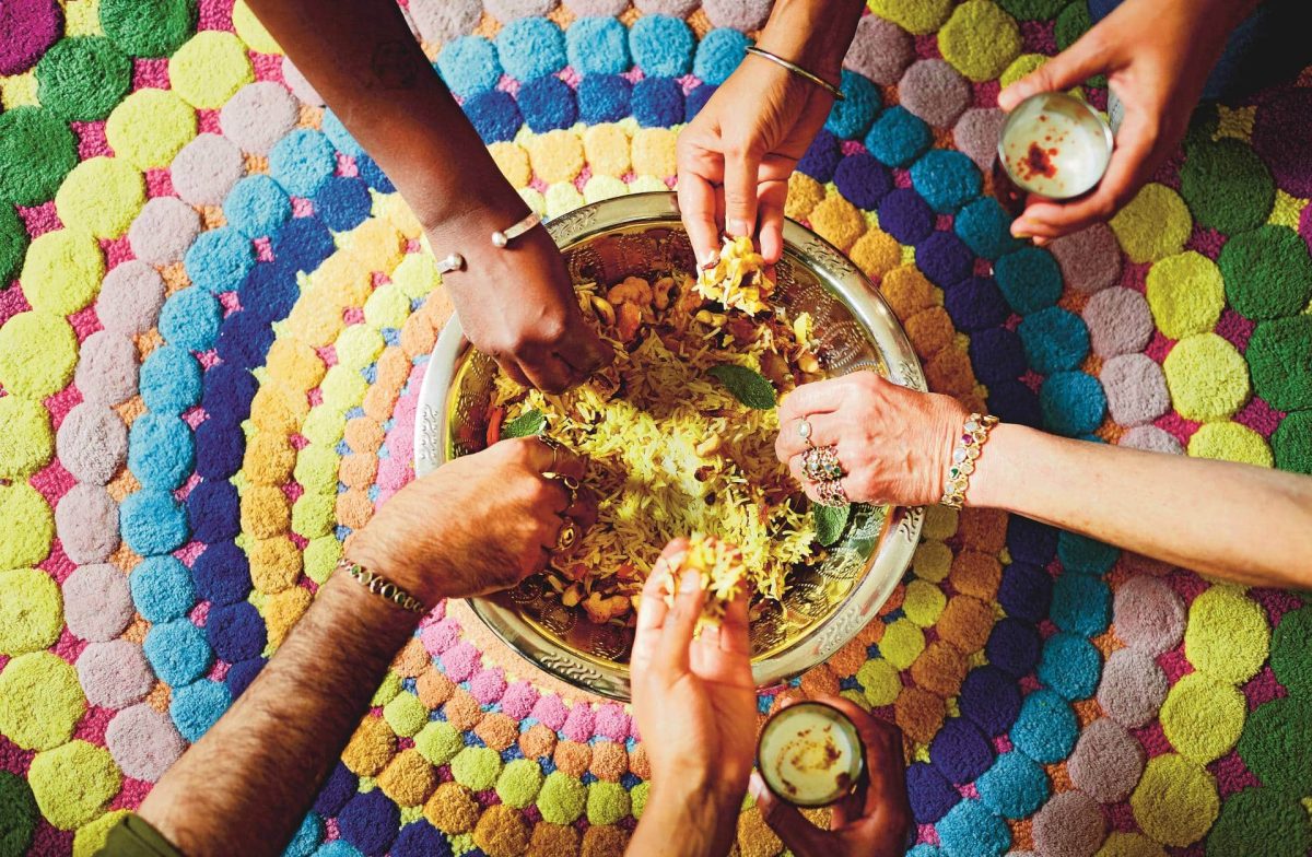 Indien vegetarisch: Viele Hände greifen in eine Schale mit Biryani, ein indisches Reisgericht.