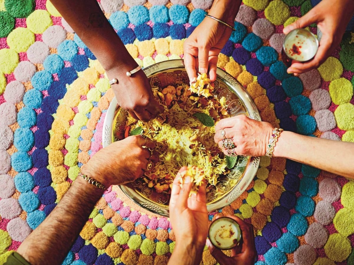Indien vegetarisch: Viele Hände greifen in eine Schale mit Biryani, ein indisches Reisgericht.