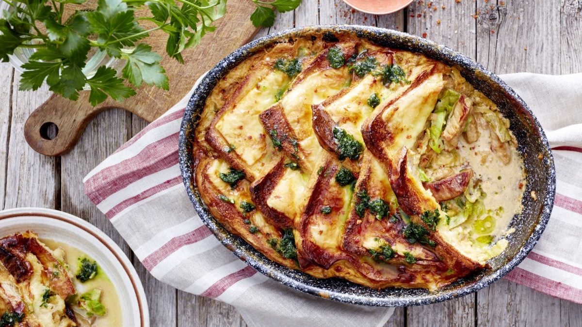 Käse-Brotauflauf in einer Auflaufform auf einem Küchentuch.