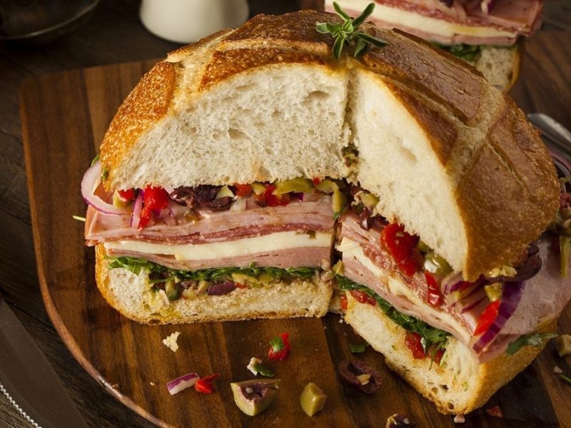 Eine Brot ist in zwei Hälften geschnitten und mit käse und schinkenbelegt.